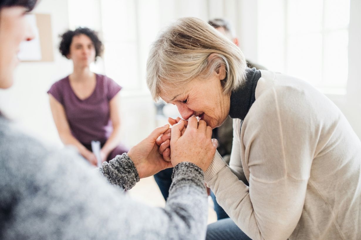 Senior lady crying in a group therapy session